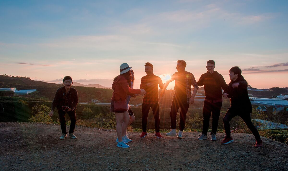 A group of young friends laughing together on a hilltop at sunset